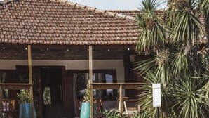 Uma área à beira da piscina com cobertura em azulejo, deck de madeira e plantas tropicais.