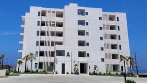Un edificio moderno de varios pisos con fachada plana, balcones y cielo despejado.