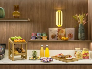 Un bufé de desayuno con diversas frutas, bollería y bebidas.