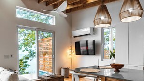 Una cucina moderna con travi in legno, una zona pranzo con tavolo e sedie, un divano e un televisore fissato alla parete.
