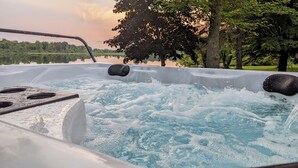 Een jacuzzi met waterstralen, omringd door bomen en een meer.