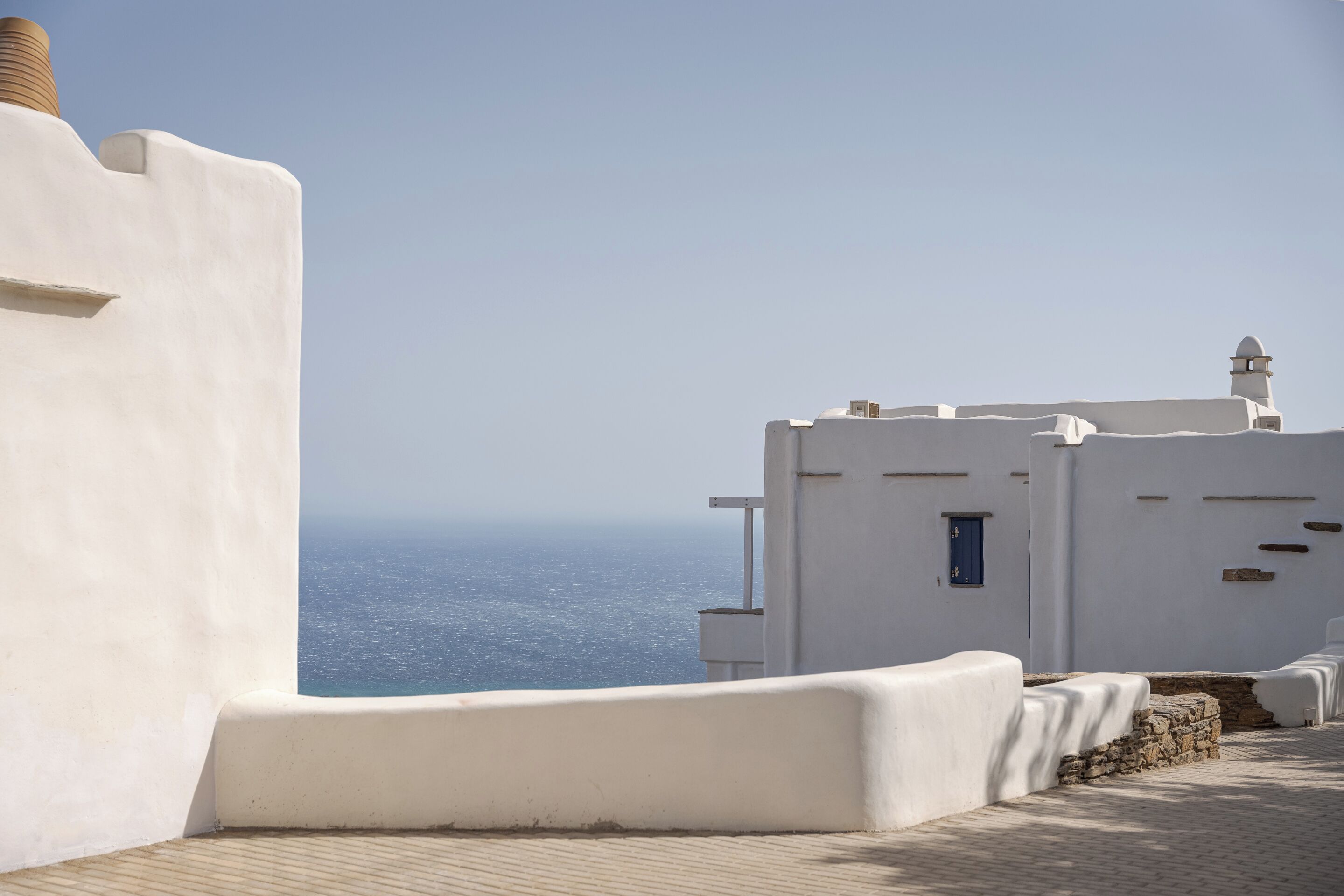Un bâtiment blanc avec un socle en pierre, une petite fenêtre et une cheminée.