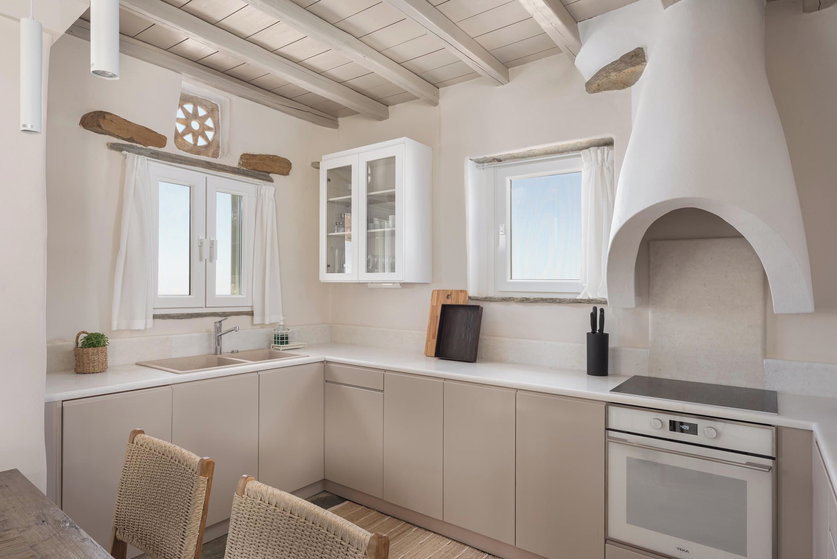 A modern kitchen with white cabinetry, a built-in oven, and a window with a view.