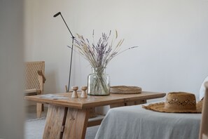 Una mesa de madera con un florero de vidrio con plantas secas, un sombrero de paja y un soporte para micrófono.