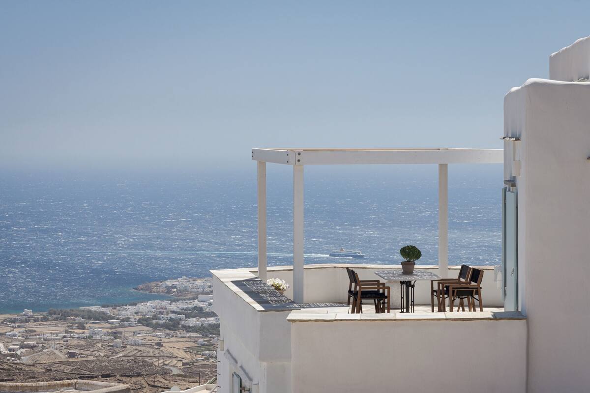 Um edifício branco com terraço e vista para a costa.