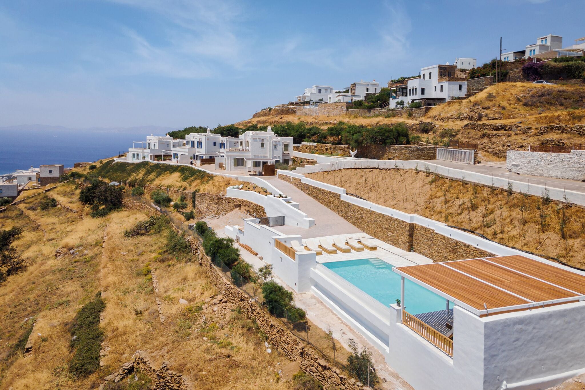 Una propiedad costera con edificios blancos, piscina y vista al mar.