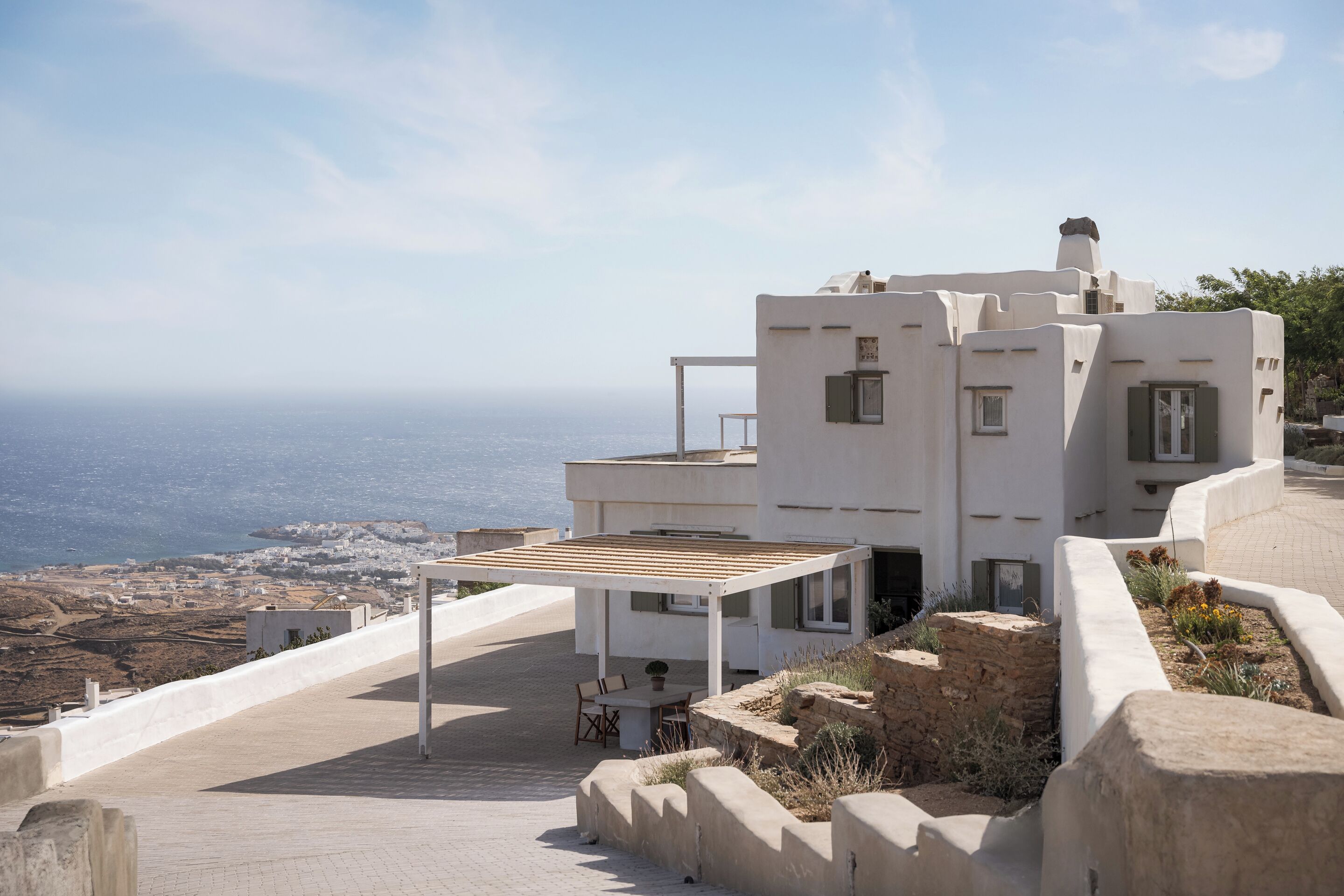 Um edifício moderno branco com um pátio e vista para a paisagem costeira.