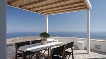 A covered outdoor seating area with a table and chairs, a potted plant, and a stone table lamp.