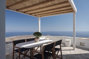 Ένας σκεπαστός εξωτερικός χώρος με τραπέζι και καρέκλες, ένα φυτό σε γλάστρα και ένα φωτιστικό τραπεζιού από πέτρα.