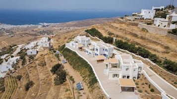 Un village côtier aux maisons blanches, avec des champs en terrasses et une vue sur la mer.