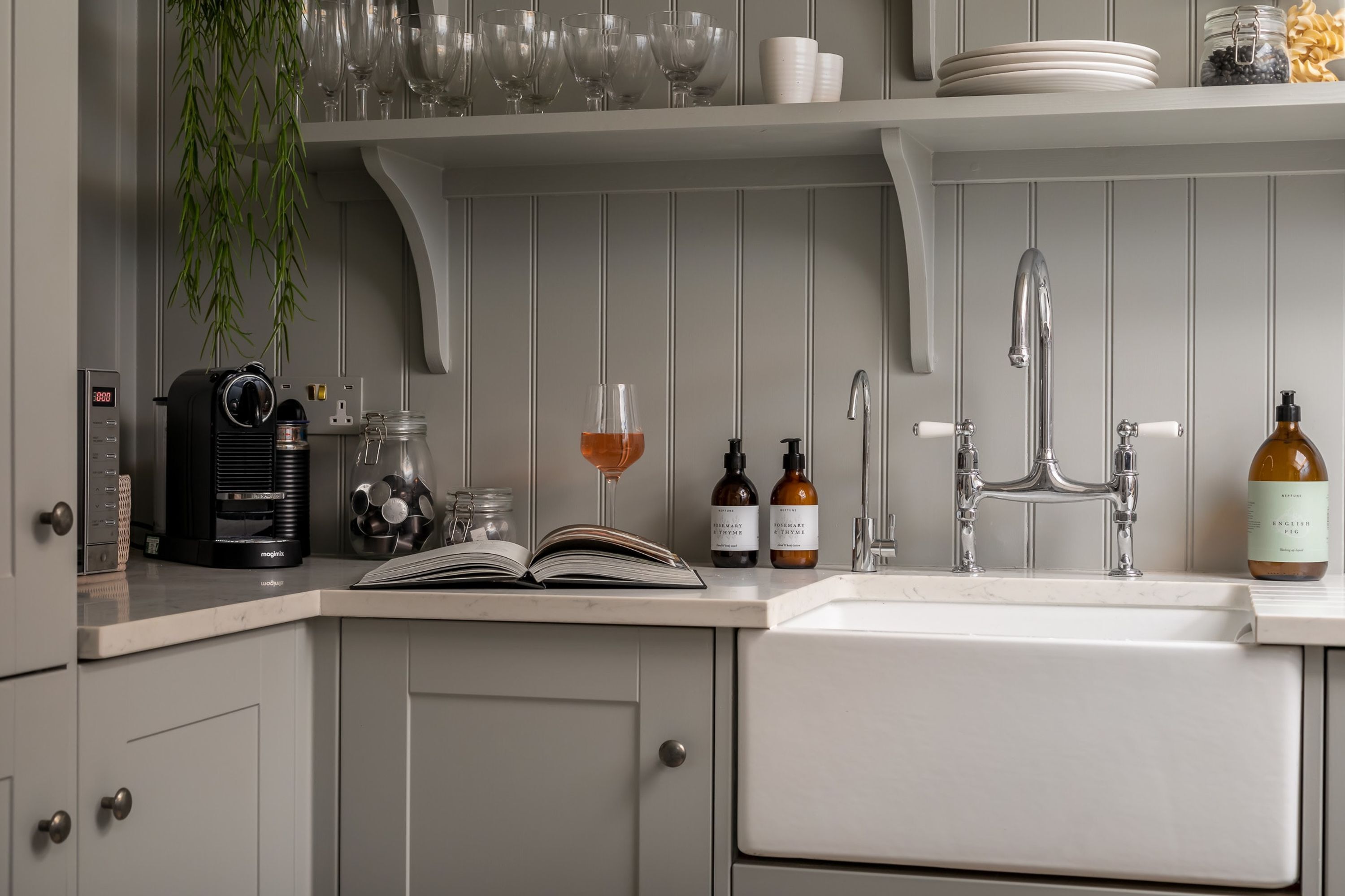 A kitchen with a coffee maker, a wine glass, and a bottle of olive oil on the counter.