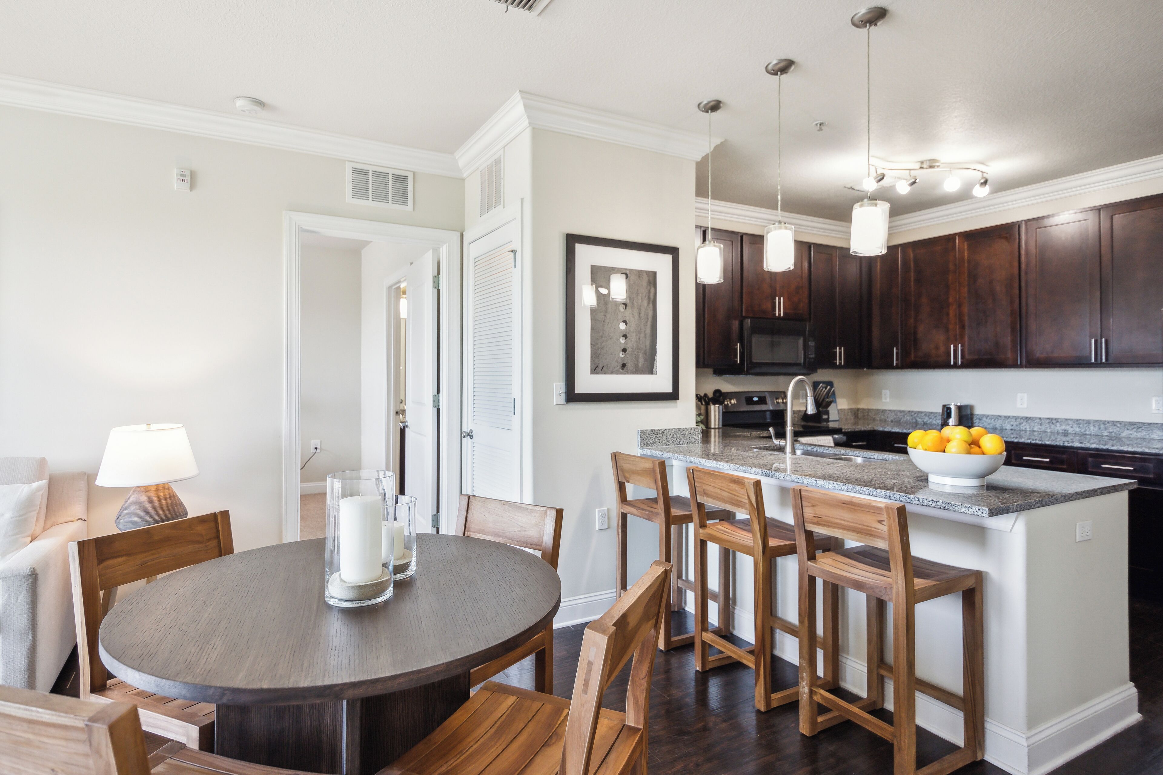 A modern kitchen with dark wood cabinets, a granite countertop, and a central island with bar stools.