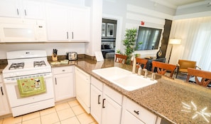 A modern kitchen with white cabinets, a granite countertop, a stove, and a sink.