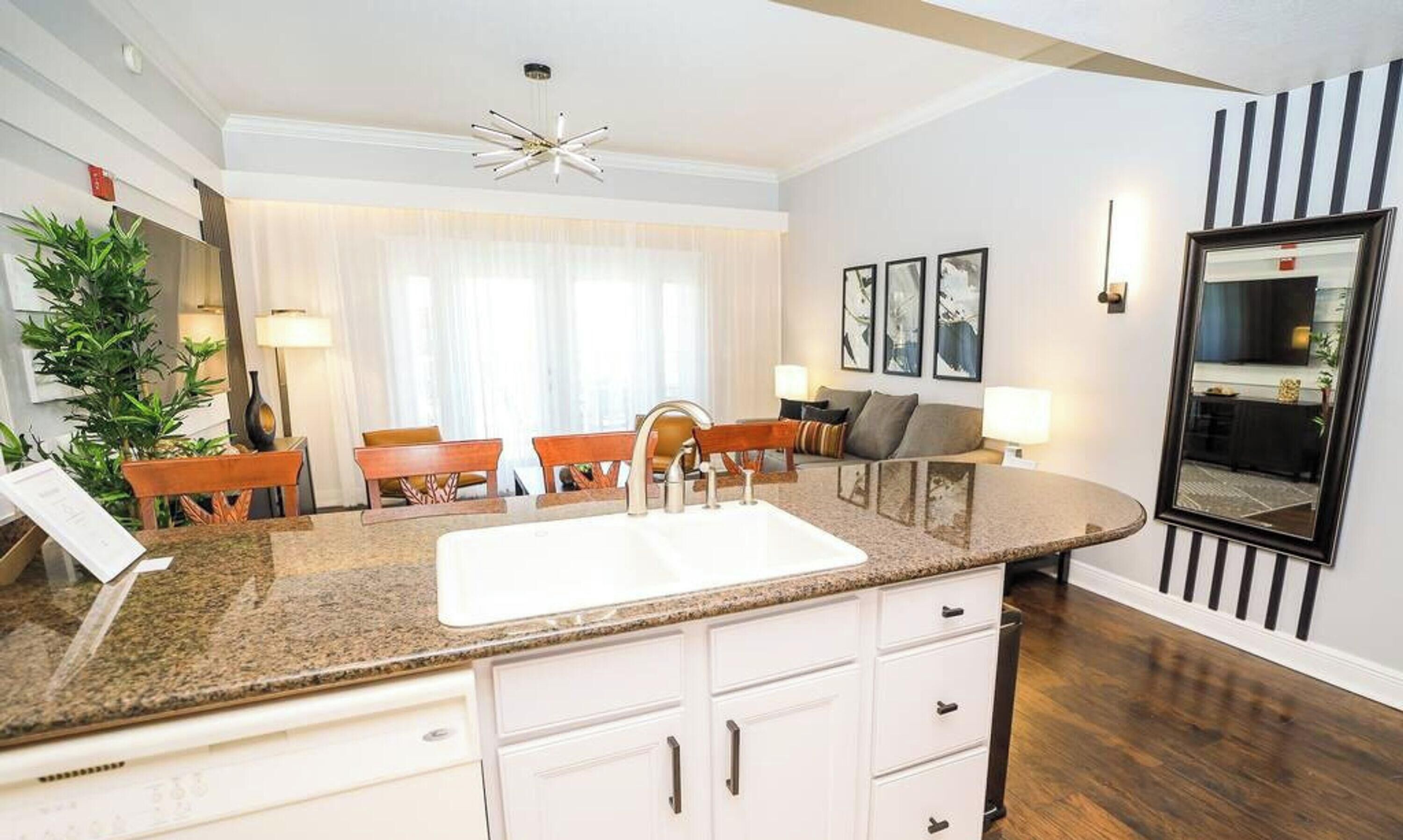 Una cucina moderna con un piano di lavoro in granito, mobili bianchi e lavello incassato.