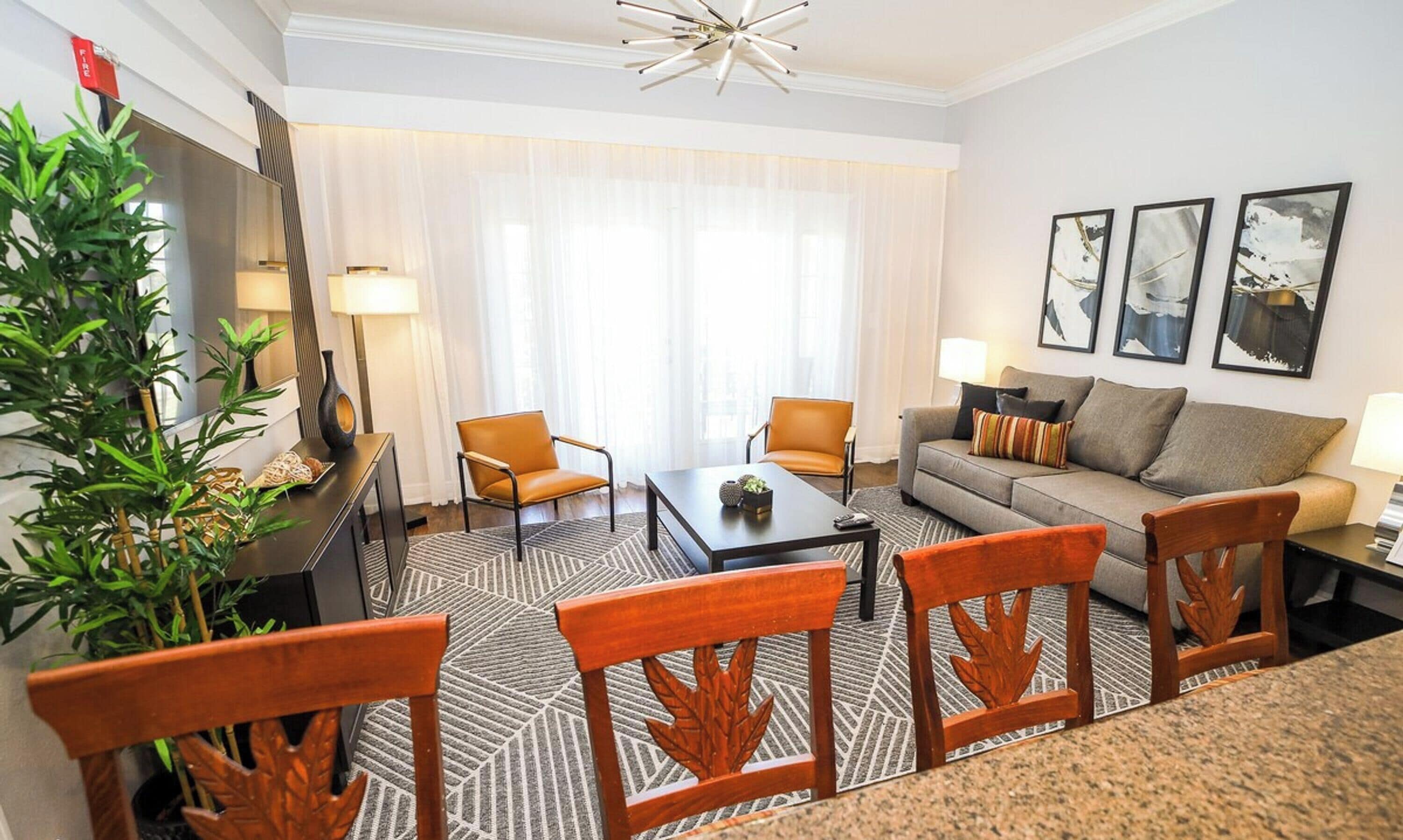 A modern living room with a sofa, two armchairs, a coffee table, and a dining area with chairs.