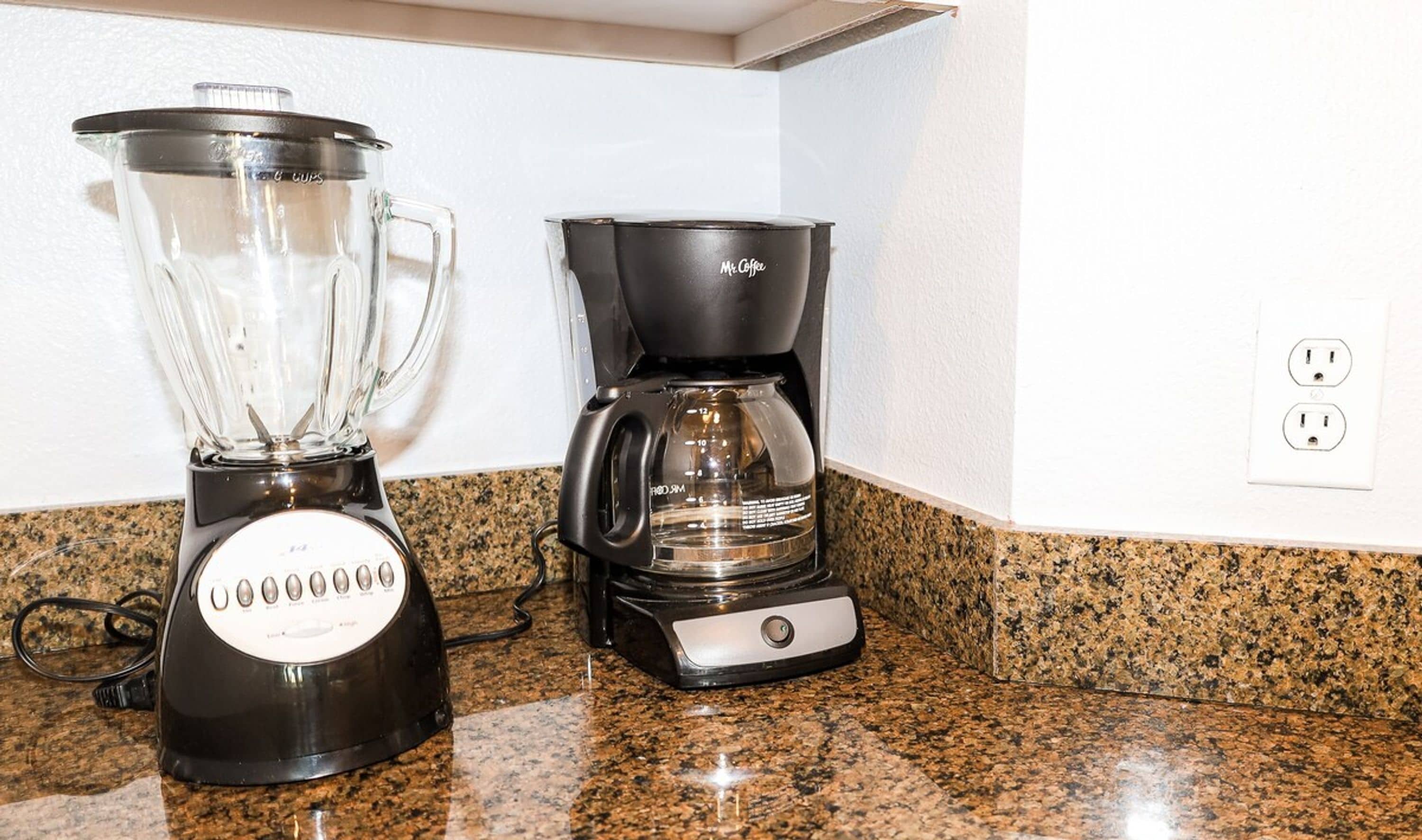 Una cocina con una licuadora y una cafetera sobre una encimera de granito.