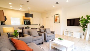 A modern living room with grey sofas, a coffee table, and a TV. - Townhome Jacuzzi Grill 10 min Disney (Kissimmee)