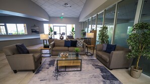 A modern lobby with sofas, a coffee table, and potted plants. - Townhome Jacuzzi Grill 10 min Disney (Kissimmee)