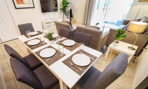 Un comedor moderno con una larga mesa dispuesta para cuatro personas, rodeada de asientos cómodos.