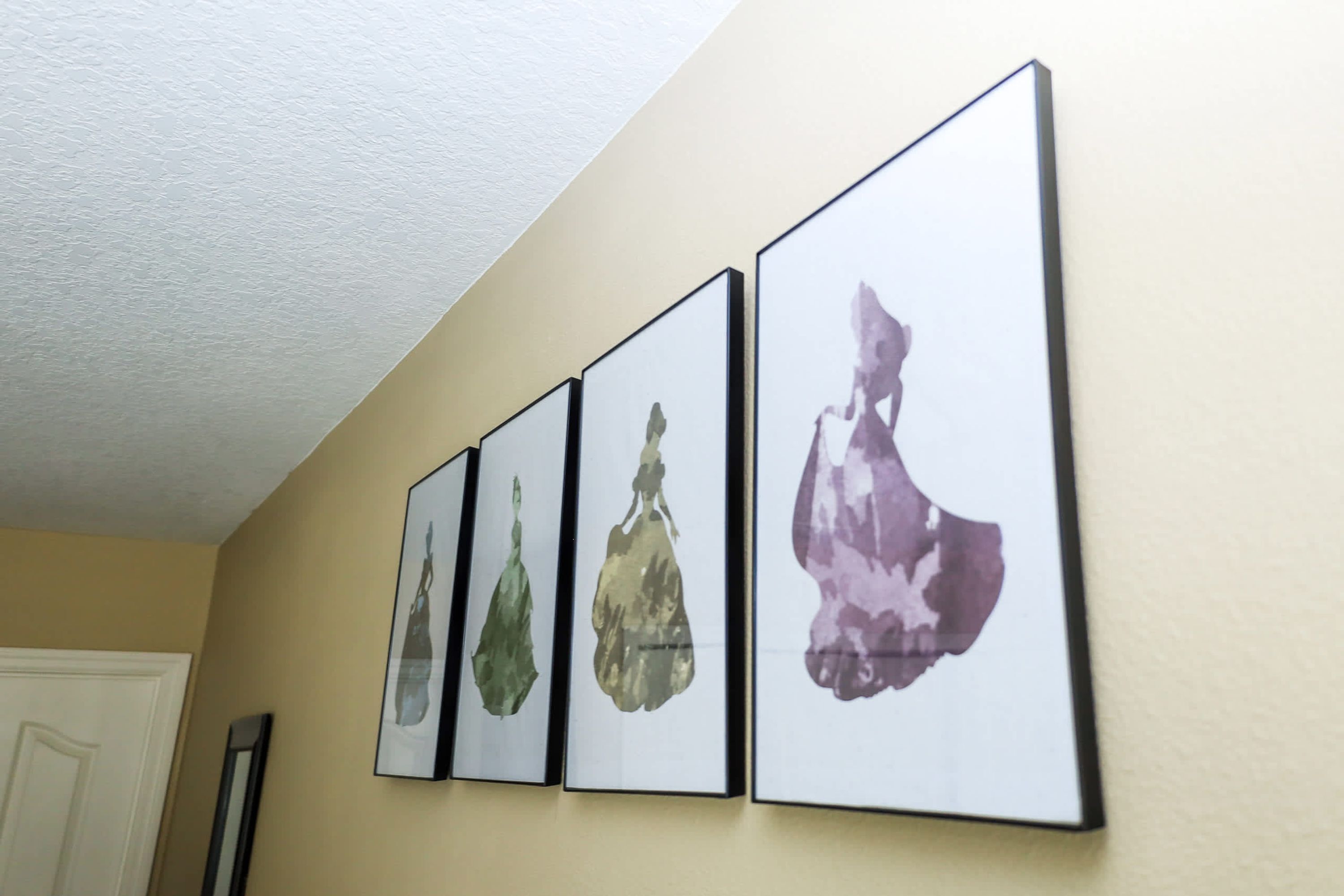 A hallway with four framed wall art pieces depicting abstract figures.