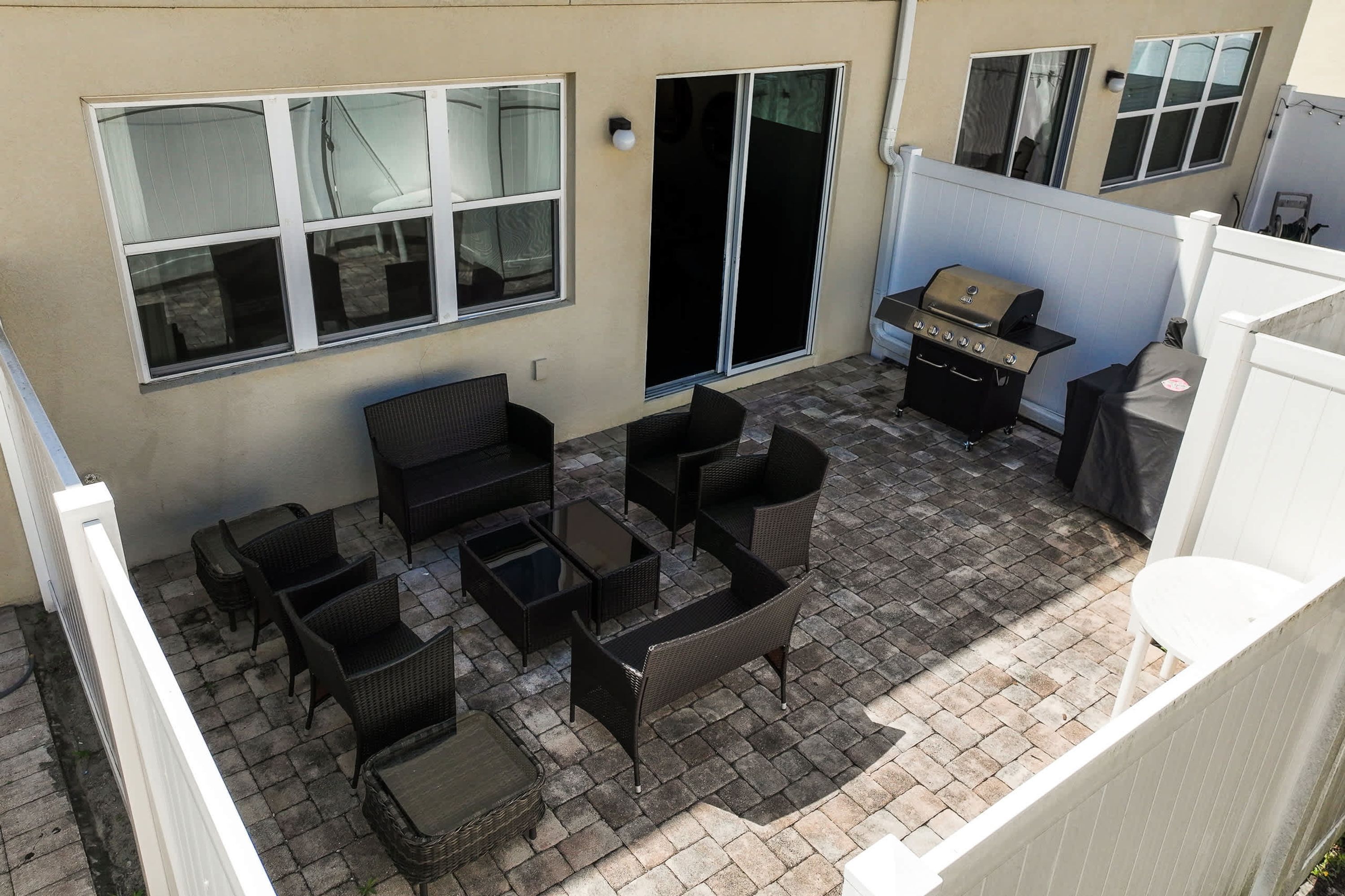 Un espace patio aménagé avec des meubles en osier, un barbecue et une porte-fenêtre coulissante.