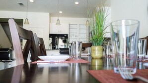 Una mesa de comedor dispuesta con cristalería transparente y una planta en maceta.