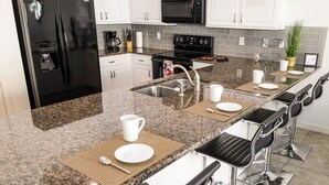 Una cocina moderna con encimeras de granito, electrodomésticos de acero inoxidable y asientos de bar.