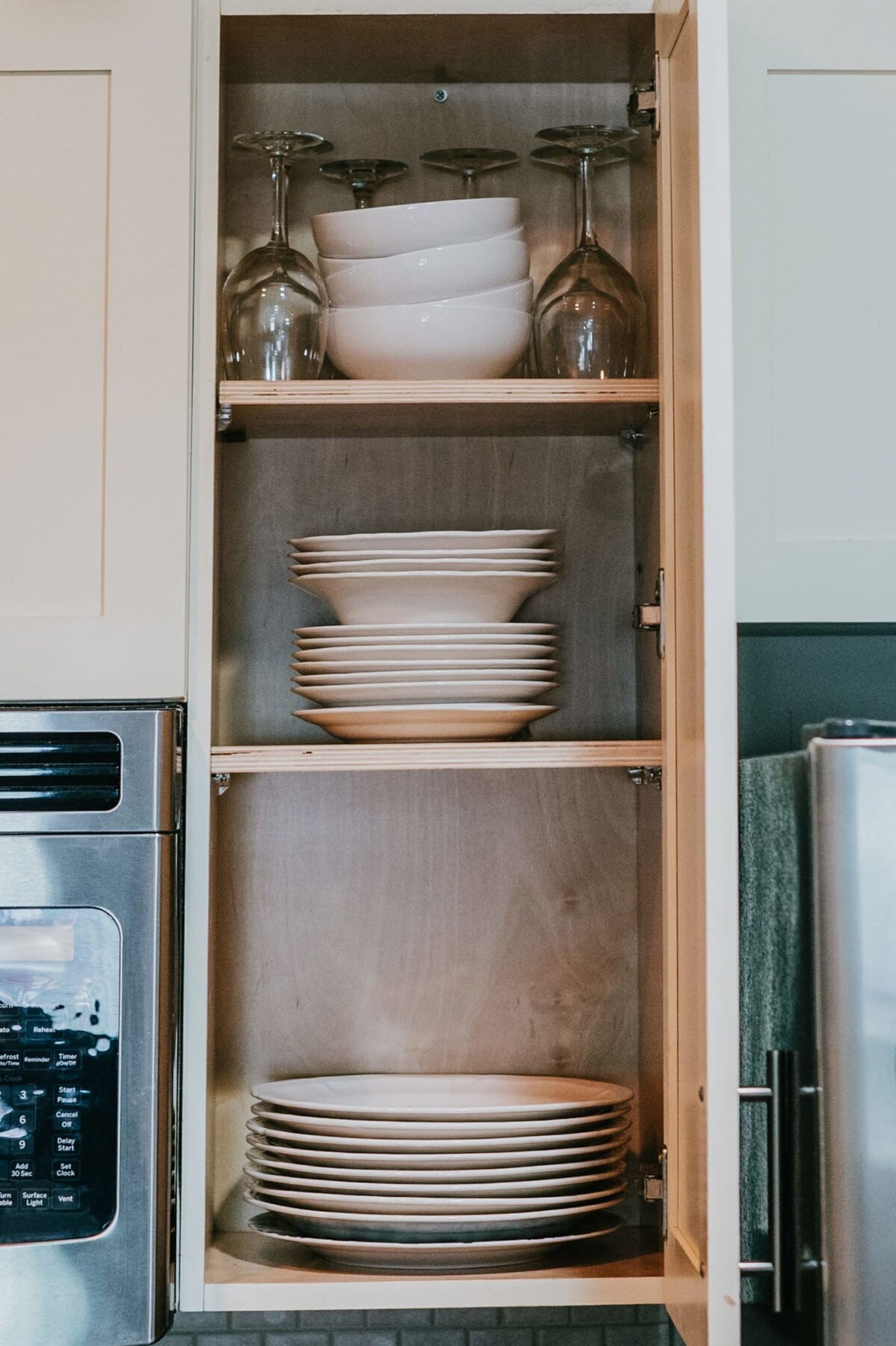 Un meuble de cuisine doté de plusieurs étagères où sont rangées des assiettes et des verres à vin.