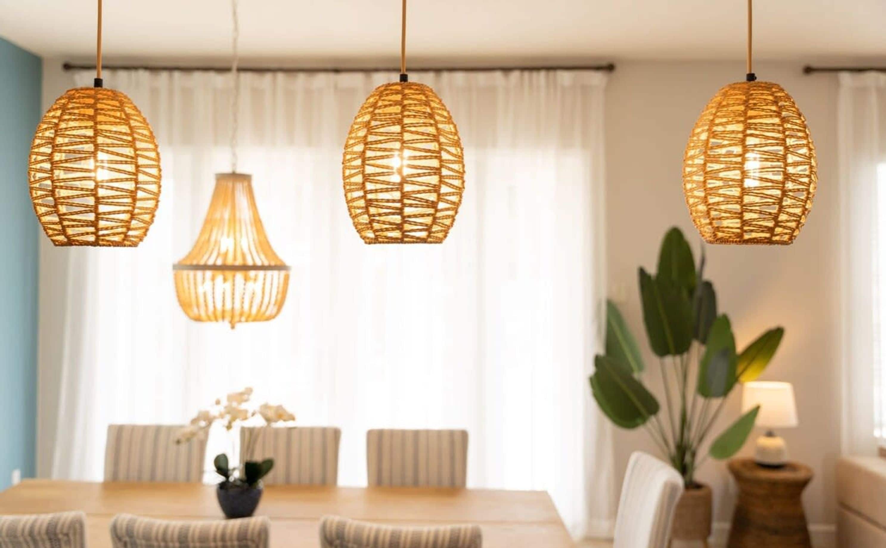 Comedor con mesa de madera, sillas a rayas y tres lámparas colgantes de fibras naturales.
