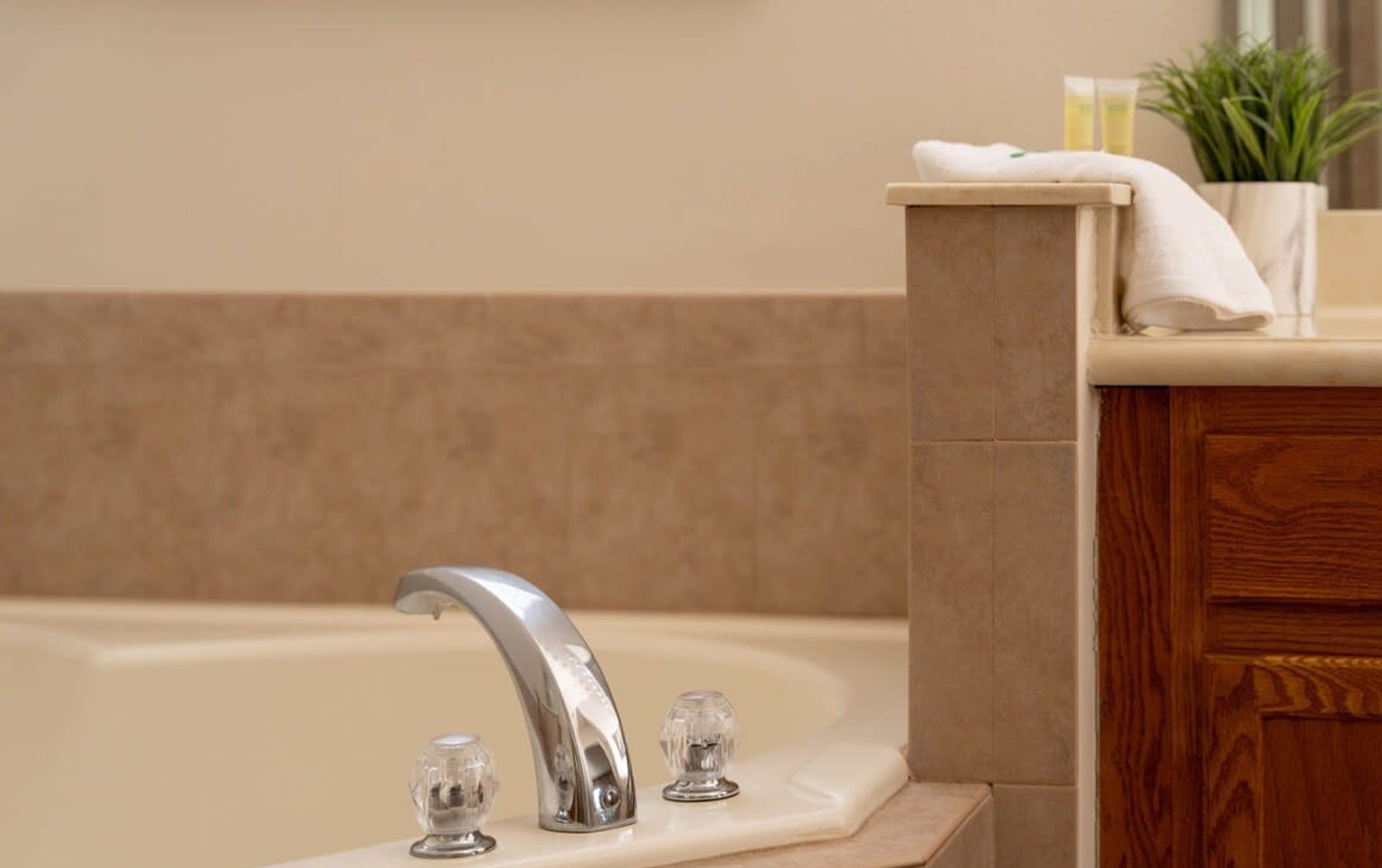 A bathroom with a bathtub, a sink with a chrome faucet, and a wooden cabinet.