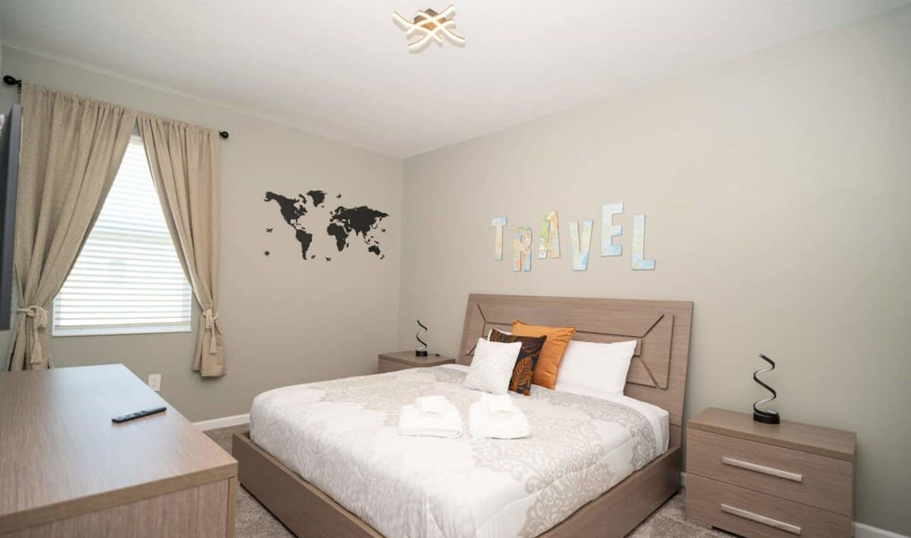 Ein Schlafzimmer mit einem Bett, einem Schreibtisch, einer Weltkarte und dem Wort "TRAVEL" an der Wand.