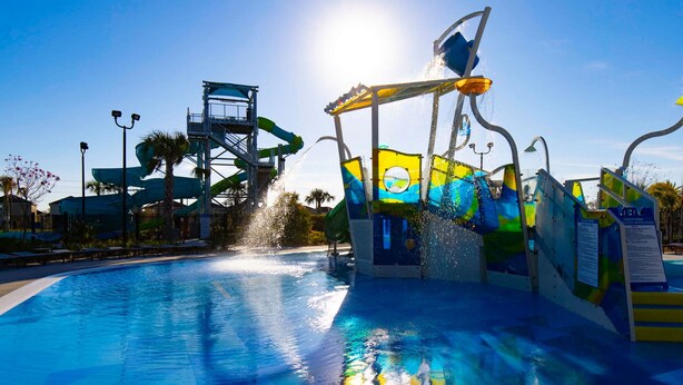 Parque acuático con una piscina grande, un tobogán de agua y un río lento.