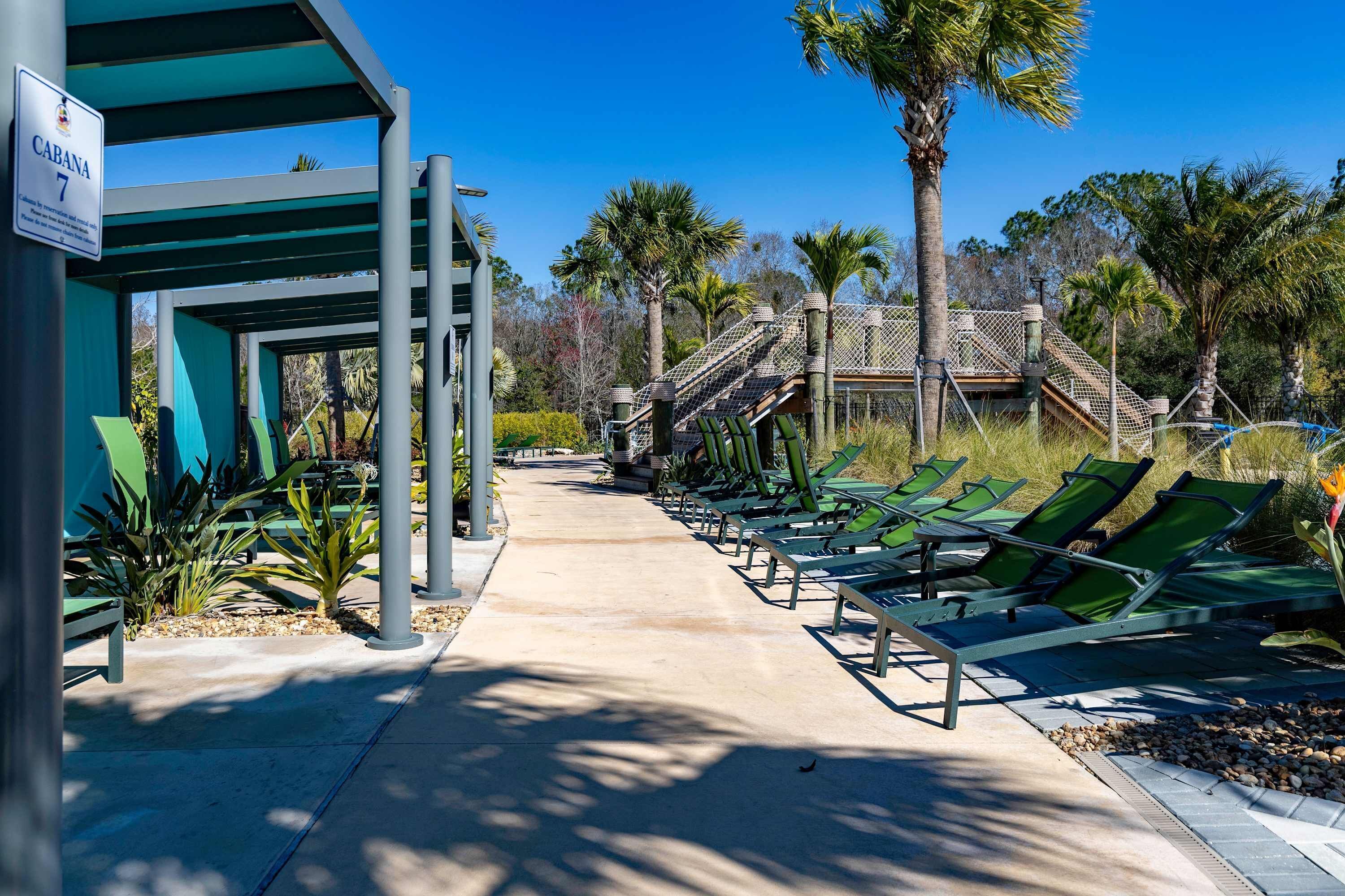 A covered outdoor area with lounge chairs, a sign reading "CABANA 7", and a staircase leading to a building.