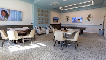 A modern lounge area with a pool table, comfortable seating, and a television screen.