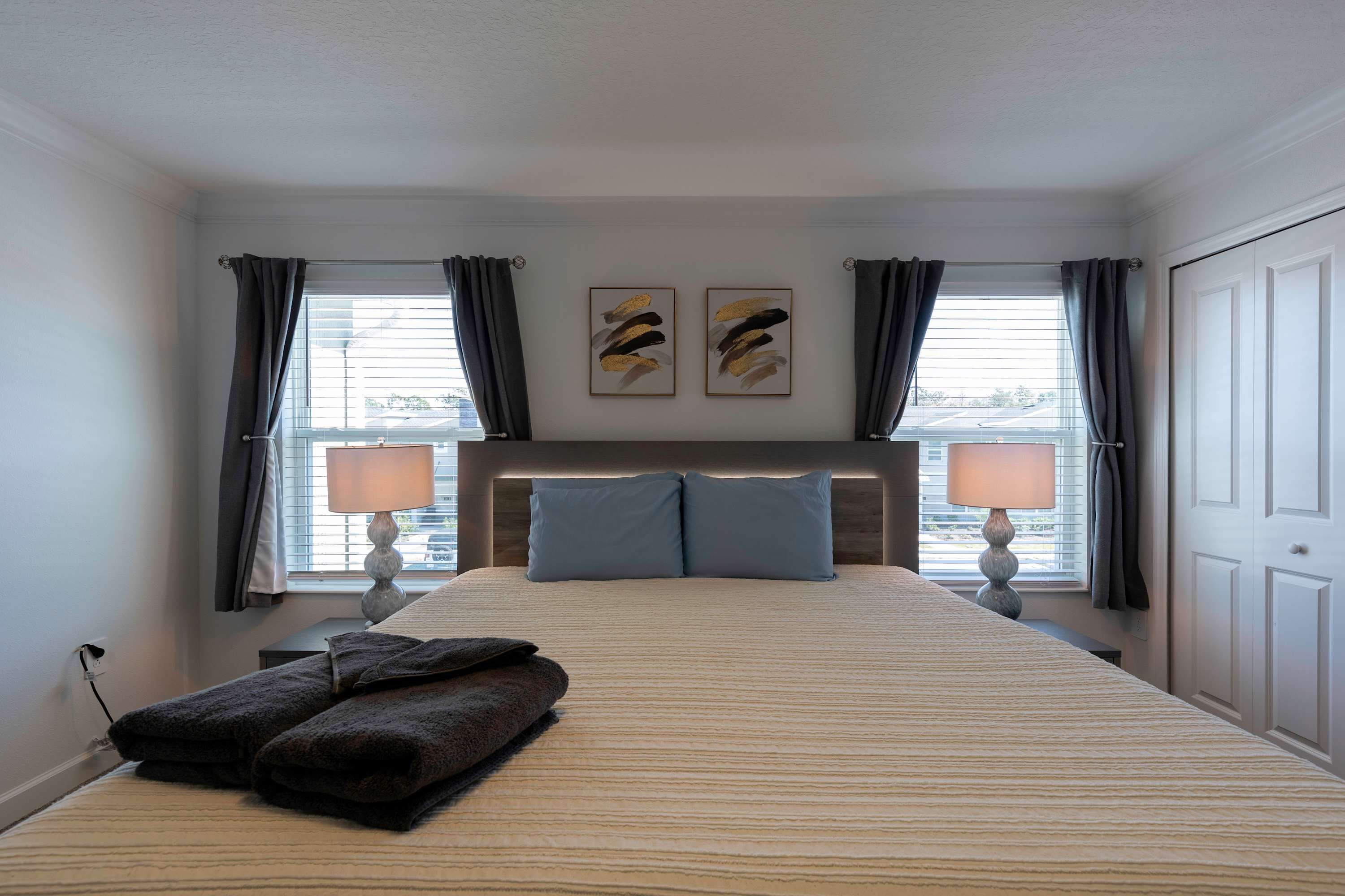 Una camera da letto ordinata con un letto grande, due lampade da comodino e vista all'esterno tramite una finestra con tende.