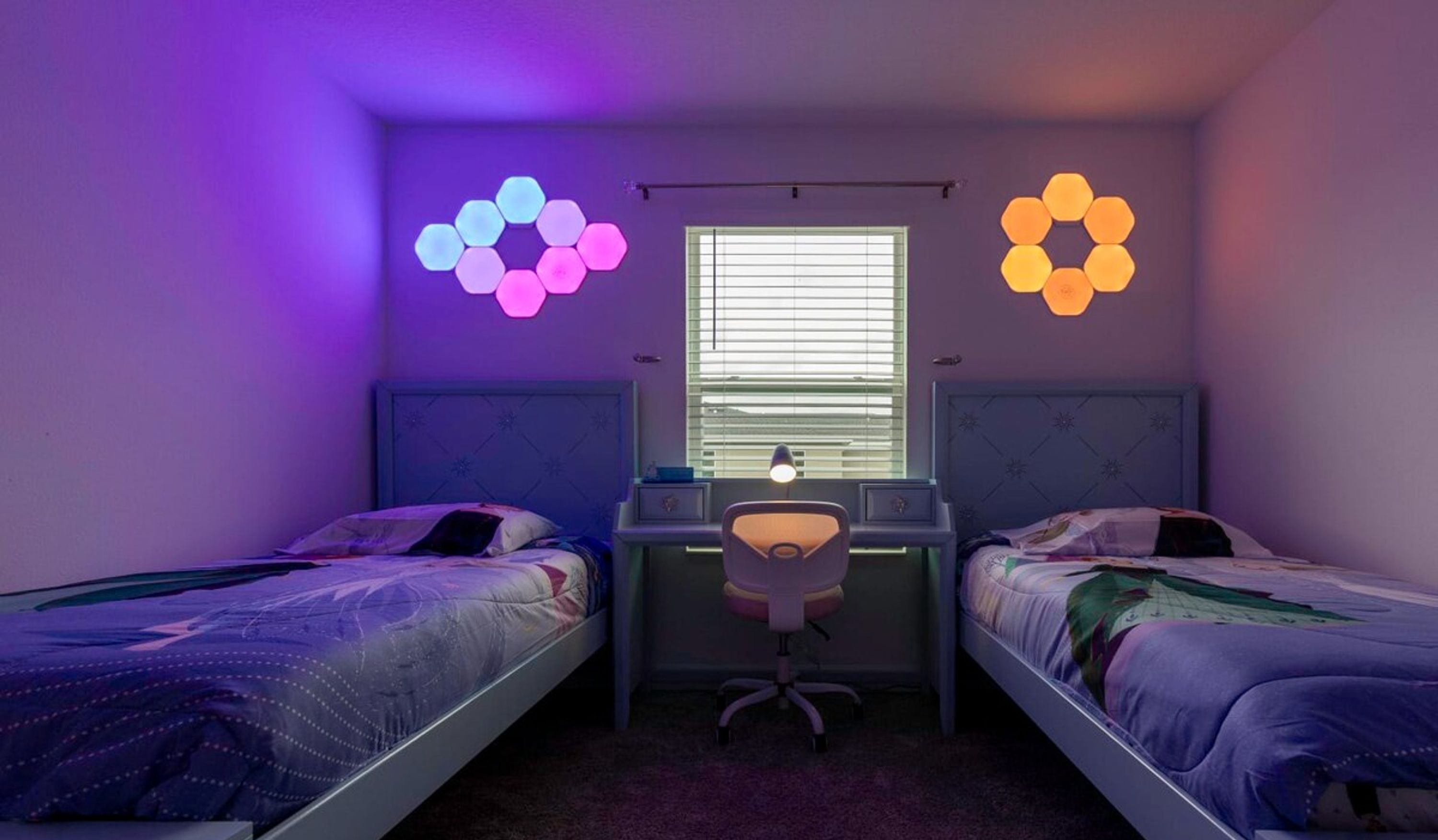 A bedroom with two beds, a desk, and a chair.