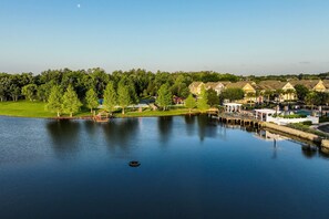 A lakeside view of a residential area with houses, a dock, and a grassy area.