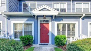 A two-story house with a red front door, white shutters, and a small porch. - Apartment Minutes From Disney (Kissimmee)