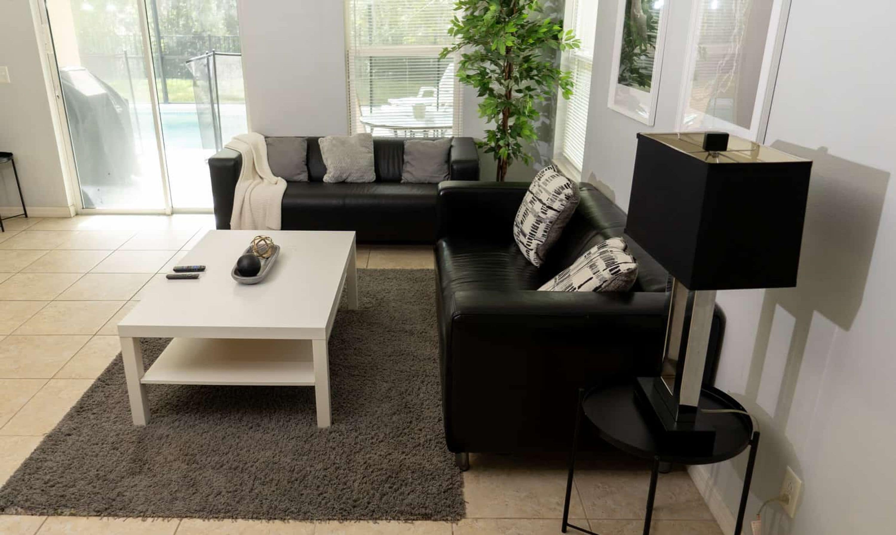 A modern living room with a black sofa, a white coffee table, a black floor lamp, and a grey rug.