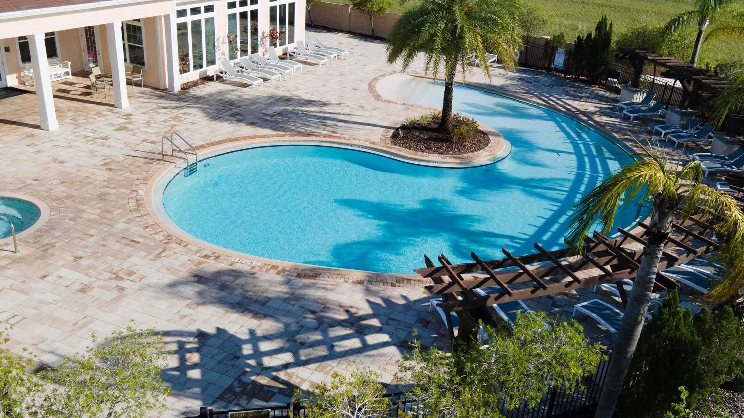 A swimming pool with a curved design, surrounded by lounge chairs and a covered seating area.