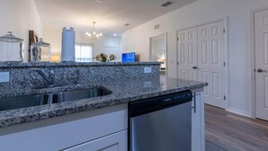 A kitchen with granite countertops, stainless steel appliances, and white cabinetry. - Fabulous Townhome Near the Parks (Kissimmee)