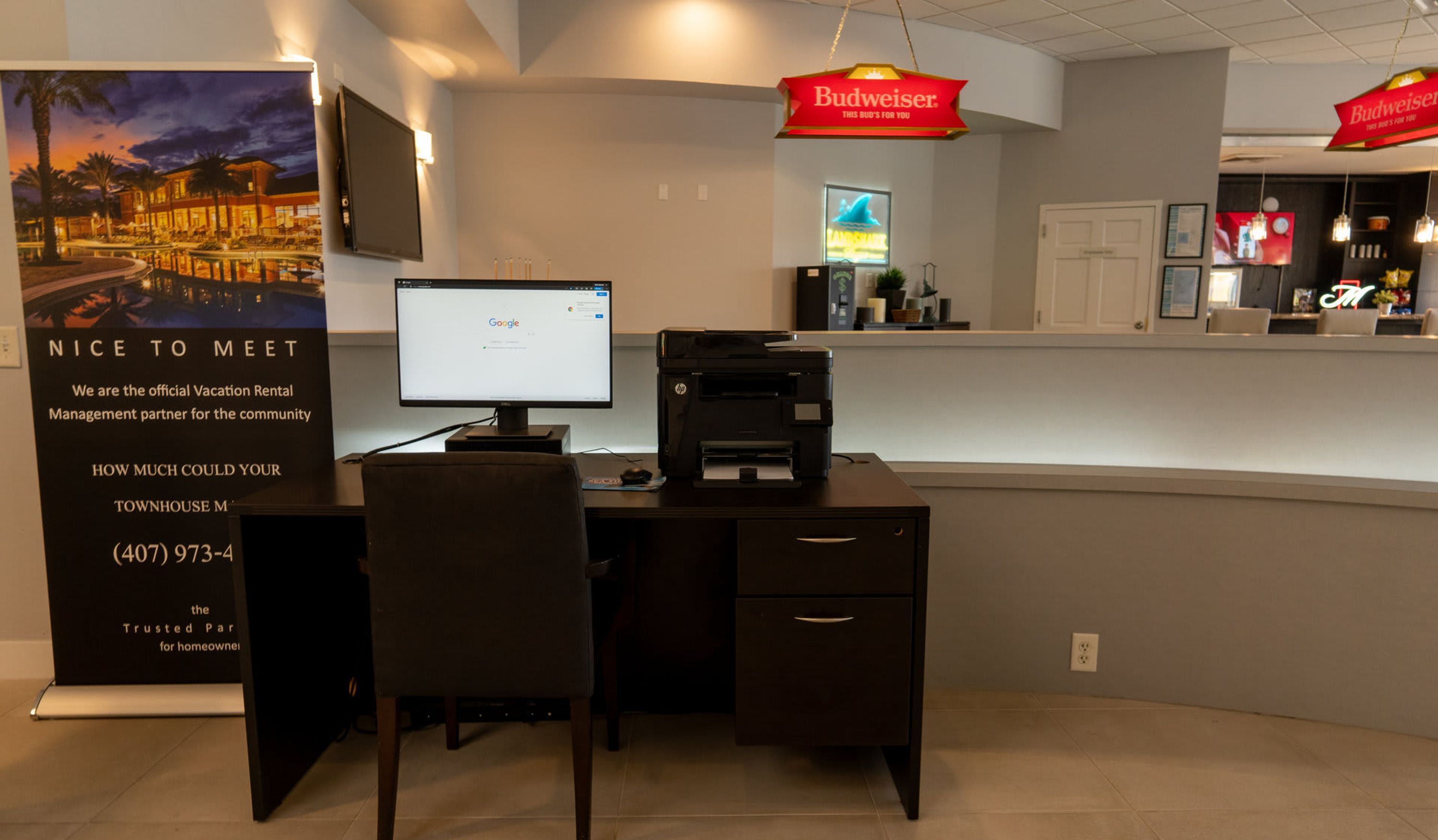 A reception desk with a computer, printer, and a Budweiser sign.