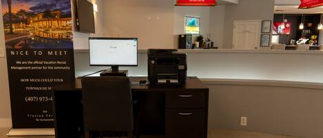 A reception desk with a computer, printer, and a Budweiser sign.