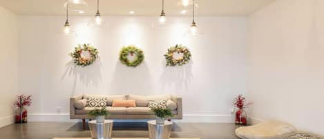 Un salon moderne comprenant un canapé, deux tables d’appoint et trois luminaires fixés au mur.