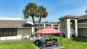A courtyard with a gazebo, palm trees, and a building with balconies. - Entire Studio With Free Shuttle to Disney (Kissimmee)