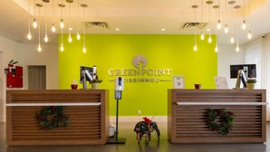 A reception area with a bright green wall, two wooden reception desks with wreaths, and a sign reading "GREENPOINT". - Entire Studio With Free Shuttle to Disney (Kissimmee)