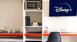 Habitación de hotel con kitchenette, cafetera, microondas y un televisor que muestra el logotipo de Disney+.