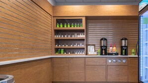 A modern kitchen with wooden cabinetry, a coffee station, and a glass-fronted beverage dispenser. - Entire Studio With Free Shuttle to Disney (Kissimmee)