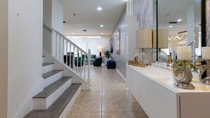 A modern interior with a staircase, a reception desk, and a living area with green sofas. - Fabulous Townhouse Near to Disney (Kissimmee)