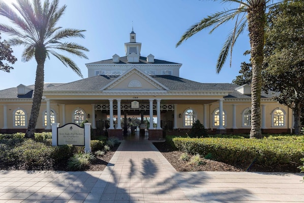 A large building with a covered walkway, palm trees, and a sign indicating it is a fitness center.